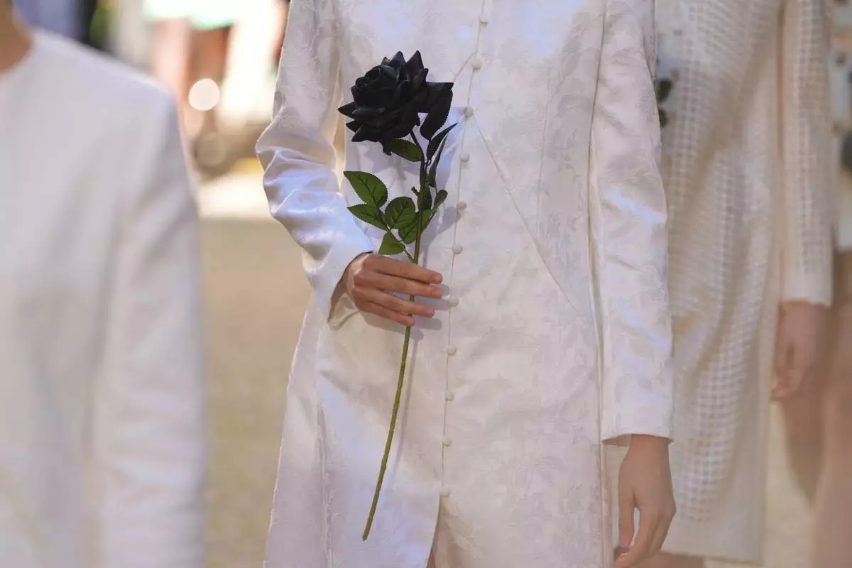 A model wears a creation as part of the Francesca Liberatore Spring/Summer 2026 collection as she holds a black rose, in Milan, Italy, Sunday, Sept. 28, 2025. (AP Photo/Antonio Calanni)