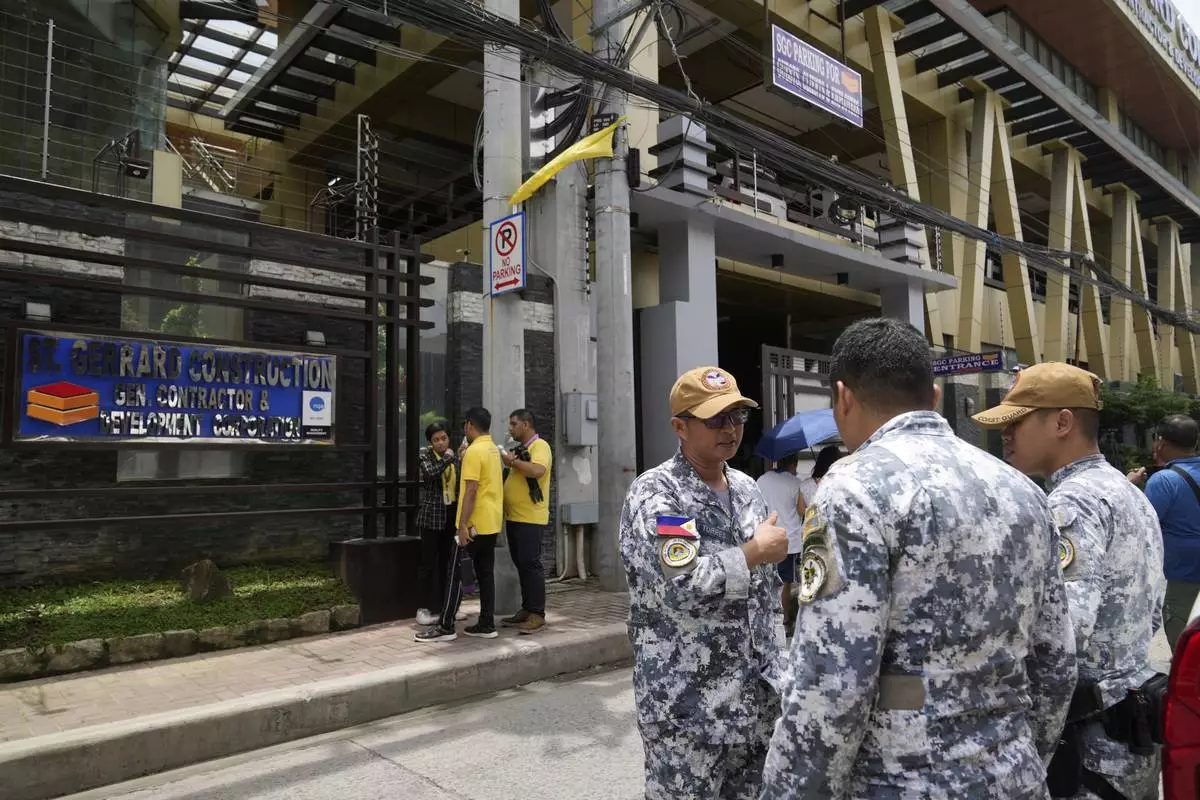 Members of the Philippine Coast Guard monitors the office of a firm owned by controversial contractors Sarah and Curlee Discaya after the Bureau of Customs served a search warrant questioning their 28 luxury cars which are believed to have been kept in their building in Pasig city, Philippines, on Tuesday, Sept. 2, 2025. (AP Photo/Aaron Favila)