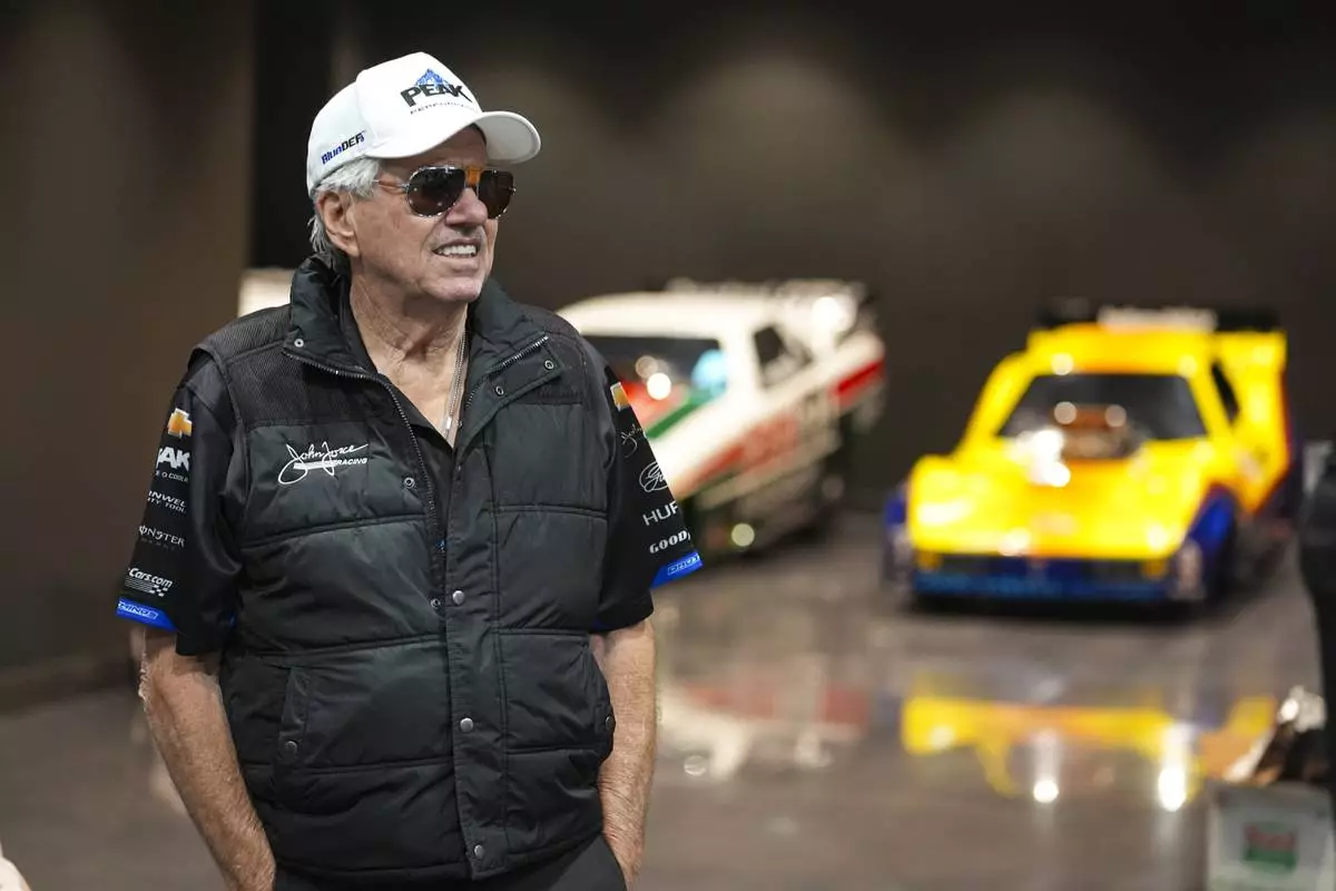 Drag racing car owner John Force poses in front of a display of the funny cars that he has driven, Thursday, Aug. 28, 2025, in Zionsville, Ind. (AP Photo/Michael Conroy)