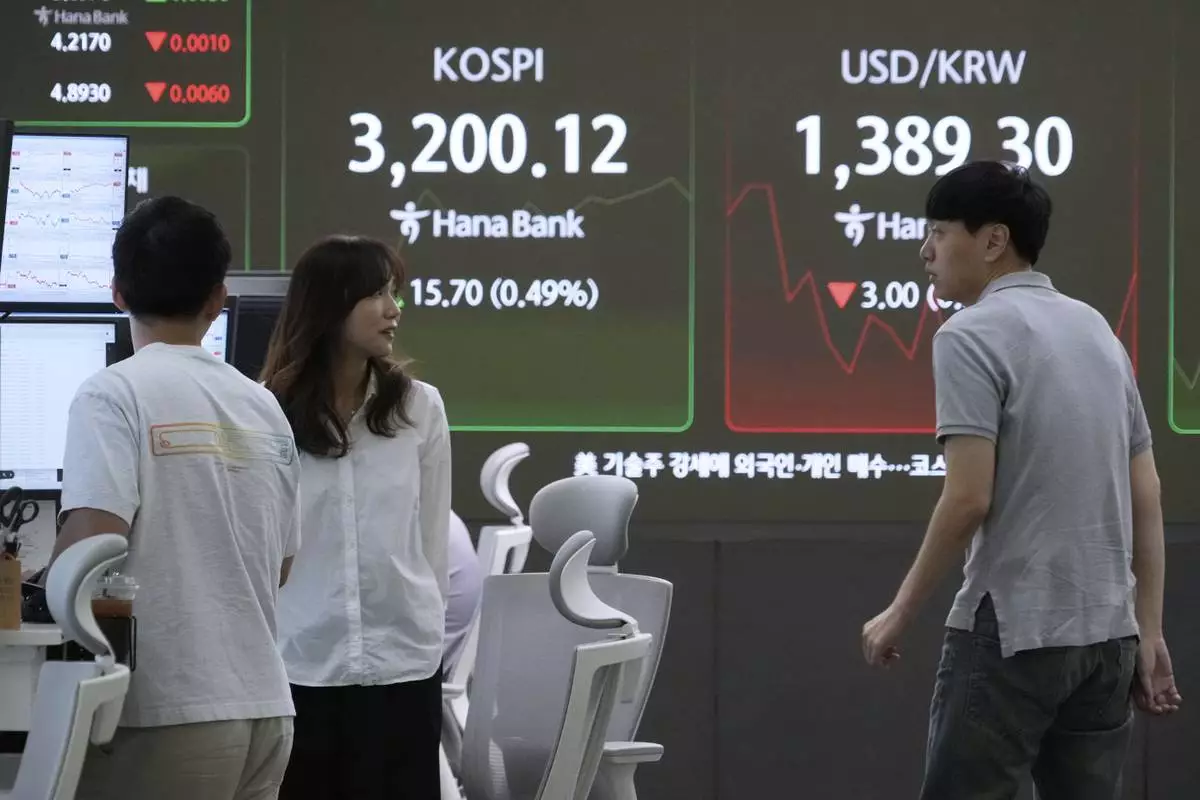 Currency traders work near a screen showing the Korea Composite Stock Price Index (KOSPI) and the foreign exchange rate between U.S. dollar and South Korean won, top right, at the foreign exchange dealing room of the Hana Bank headquarters in Seoul, South Korea, Thursday, Sept. 4, 2025. (AP Photo/Ahn Young-joon)