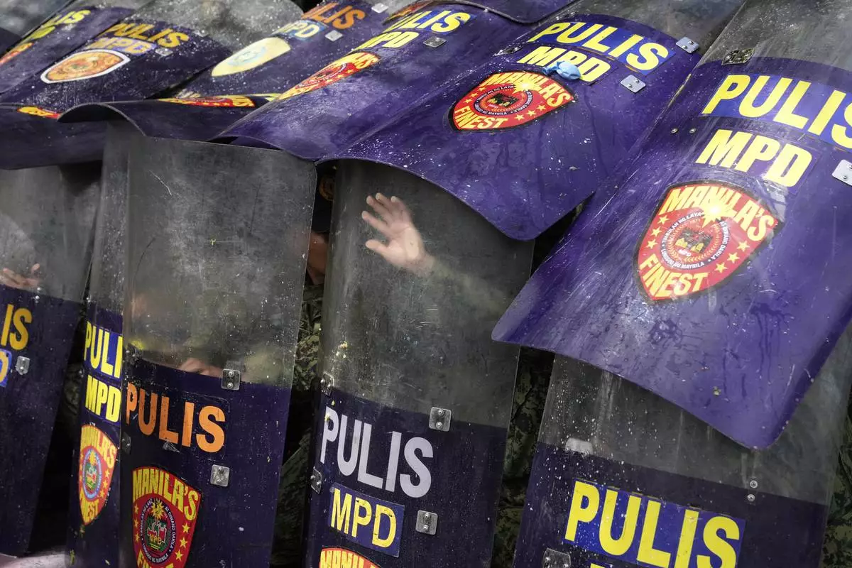 Policemen use their shields for protection as protesters throw balloons filled with dirty water during a rally outside the Philippine Department of Public Works and Highways to condemn the massive corruption in flood control projects that may implicate public works officials and engineers, construction firms and politicians in a scandal that has sparked public outrage online on Thursday, Sept. 4, 2025, in Manila, Philippines. (AP Photo/Aaron Favila)