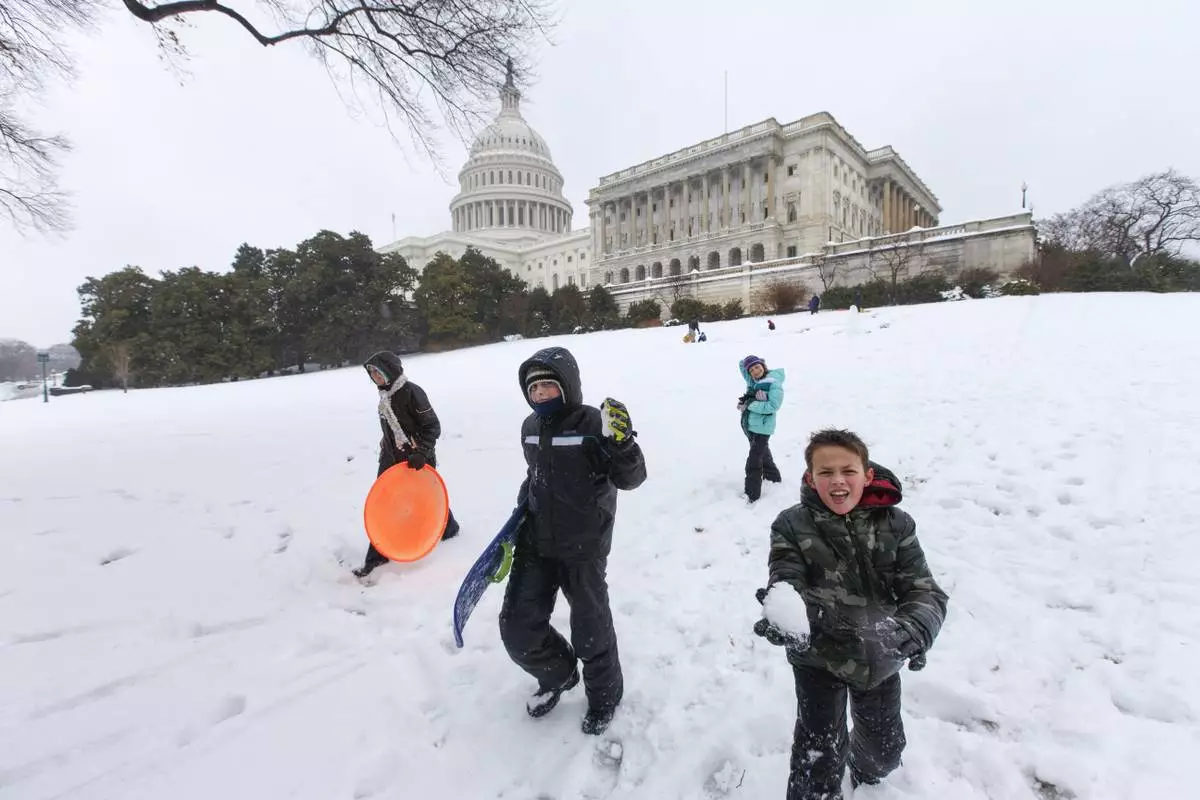 FILE - Children play in the snow around the Capitol as winter weather shuts down Washington, Feb. 13, 2014. (AP Photo/J. Scott Applewhite, File)