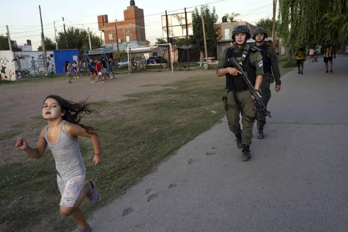 FILE PHOTO GALLERY - A girl runs past as border police agents patrol Los Pumitas neighborhood, where an 11-year-old boy was killed days earlier when at least one gunmen attacked a birthday party, amid escalating drug violence in Rosario, Argentina, March 9, 2023. (AP Photo/Rodrigo Abd)