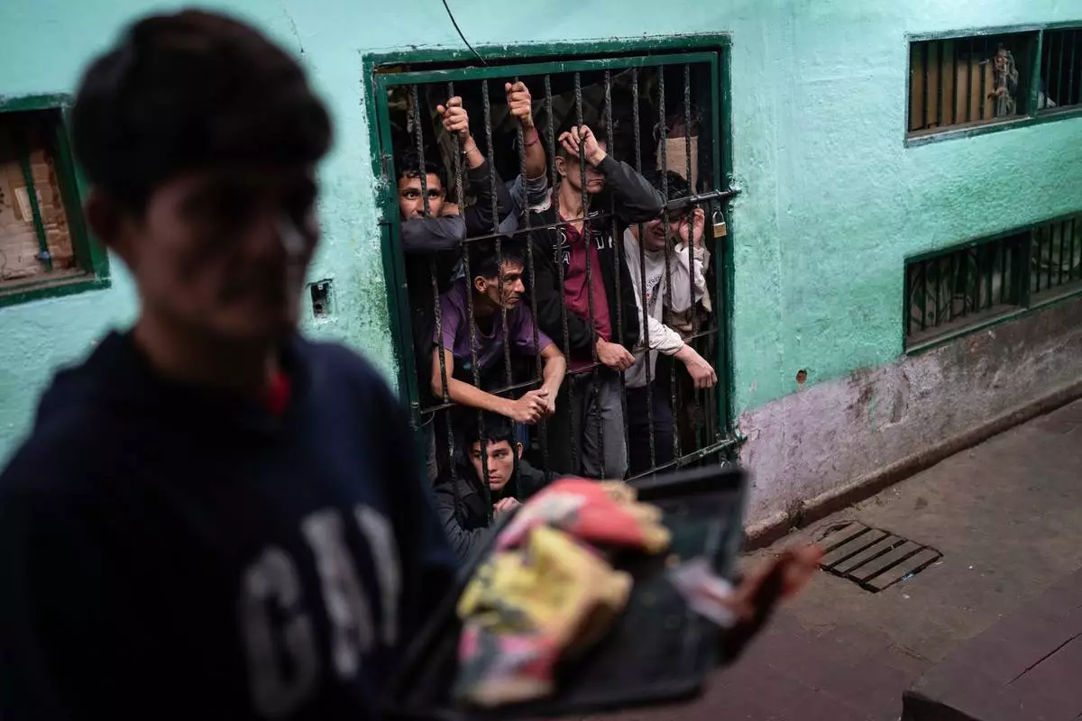FILE PHOTO GALLERY - Prisoners peer out from their group cell in the late afternoon as another prisoner prepares to enter another group cell at the Regional Penitentiary in Villarica, Paraguay, Aug. 31, 2024. (AP Photo/Rodrigo Abd)