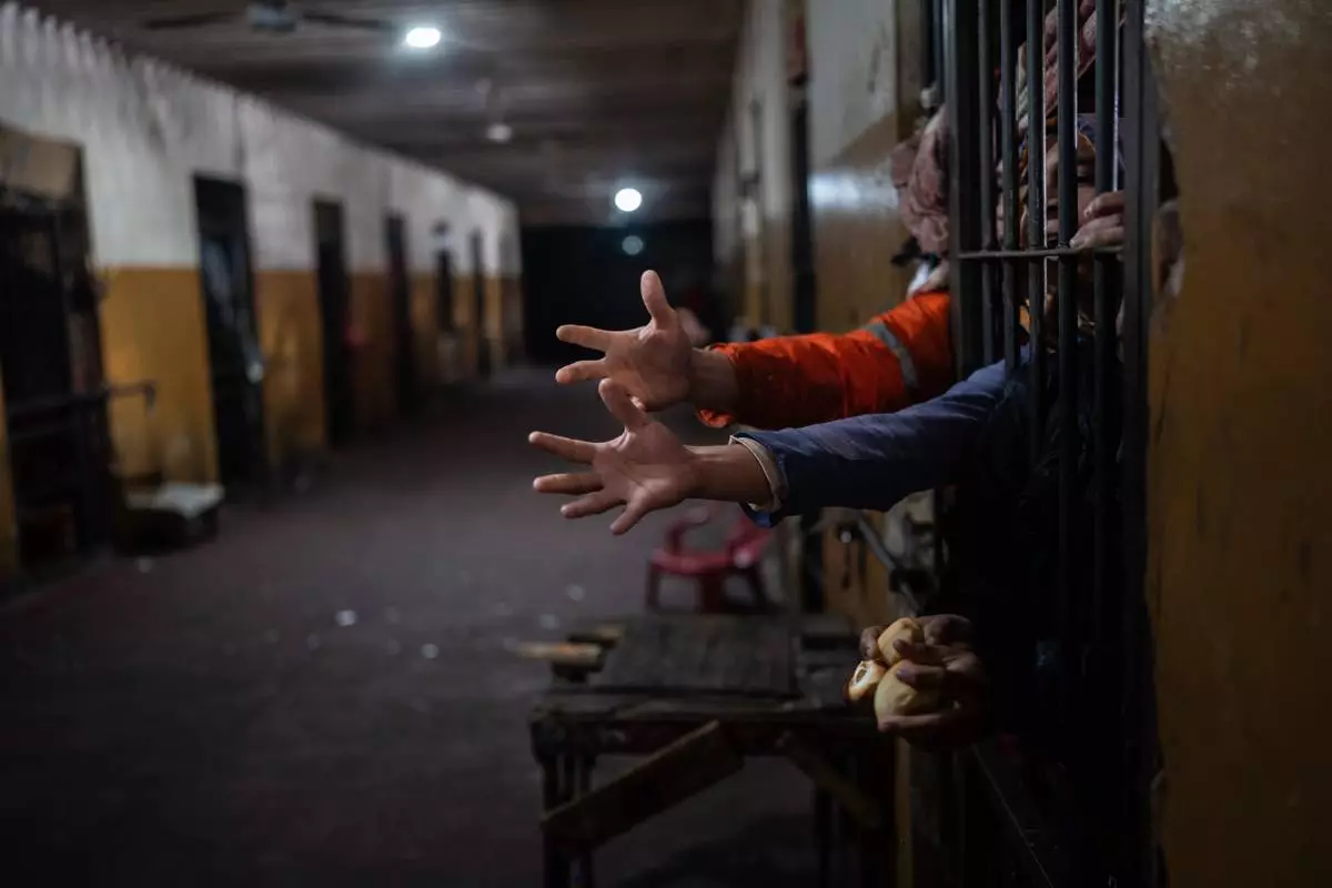FILE PHOTO GALLERY - Inmates reach out from their cell to receive bread at lunchtime at the Juan de la Vega prison in Emboscada, Paraguay, July 12, 2024. (AP Photo/Rodrigo Abd)