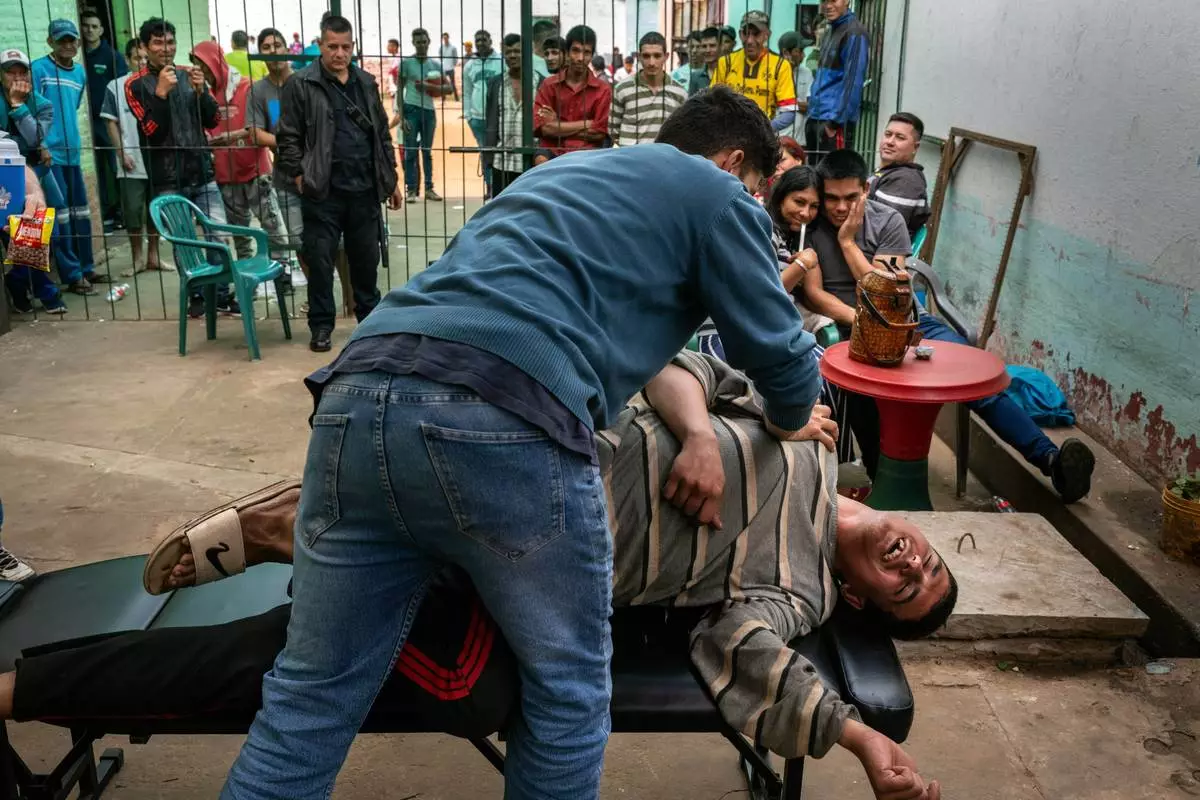 FILE PHOTO GALLERY - An inmate giggles as a volunteer physical therapist provides a free stretching session during visitors day at the Regional Penitentiary in Villarica, Paraguay, Sept. 1, 2024. (AP Photo/Rodrigo Abd)