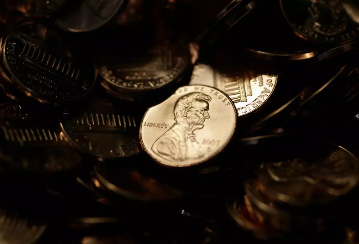 FILE - A lone penny is illuminated in a bin of completed pennies at the U.S. Mint in Denver on Aug. 15, 2007. (AP Photo/David Zalubowski, File)