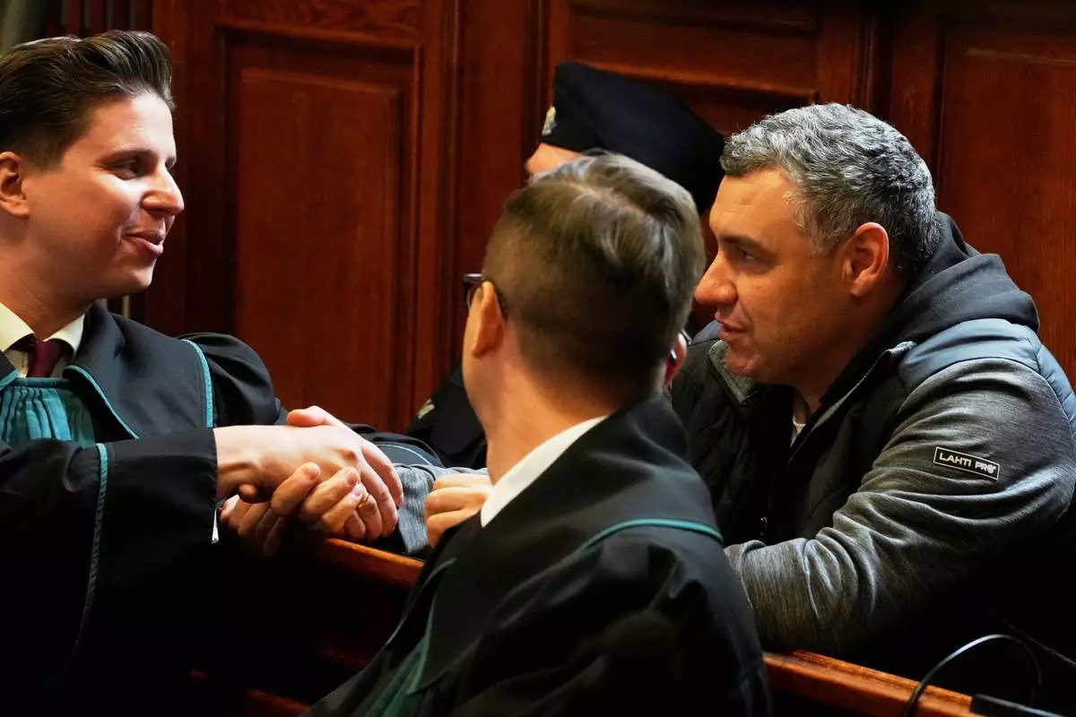CAPTION CORRECTS THE SPELLING - Ukrainian defendant Volodymyr Zhuravlov, right, shakes hands with his lawyer Tymoteusz Paprocki, left, as a judge announce the decision not to allow for extradition to Germany in courtroom of Warsaw's Regional Court in Warsaw, Poland, Friday, Oct. 17, 2025. (AP Photo/Czarek Sokolowski)