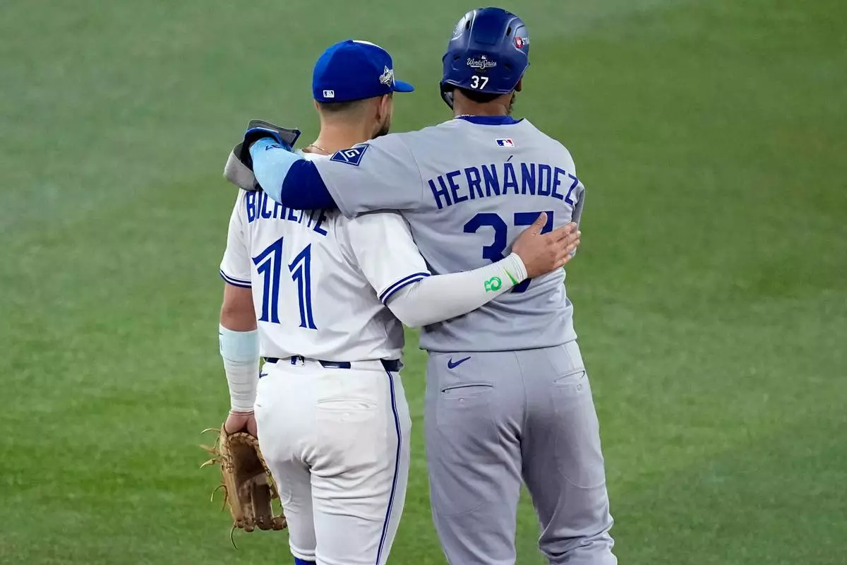 Los Angeles Dodgers' Teoscar Hernández (37) hugs Toronto Blue Jays' Bo Bichette during the second inning in Game 1 of baseball's World Series, Friday, Oct. 24, 2025, in Toronto. (AP Photo/David J. Phillip)