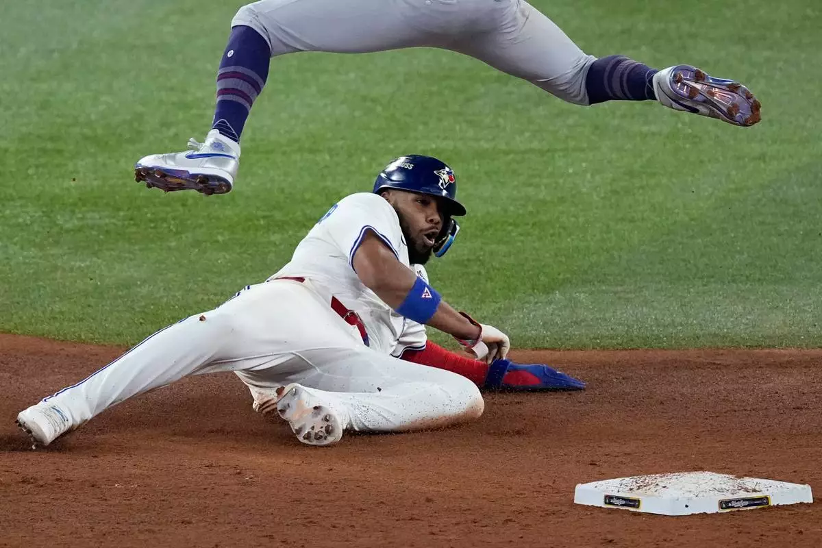 Toronto Blue Jays' Vladimir Guerrero Jr. is forced out at second as he slides under Los Angeles Dodgers' Mookie Betts on a double play hit into by Bo Bichette during the third inning in Game 1 of baseball's World Series, Friday, Oct. 24, 2025, in Toronto. (AP Photo/David J. Phillip)