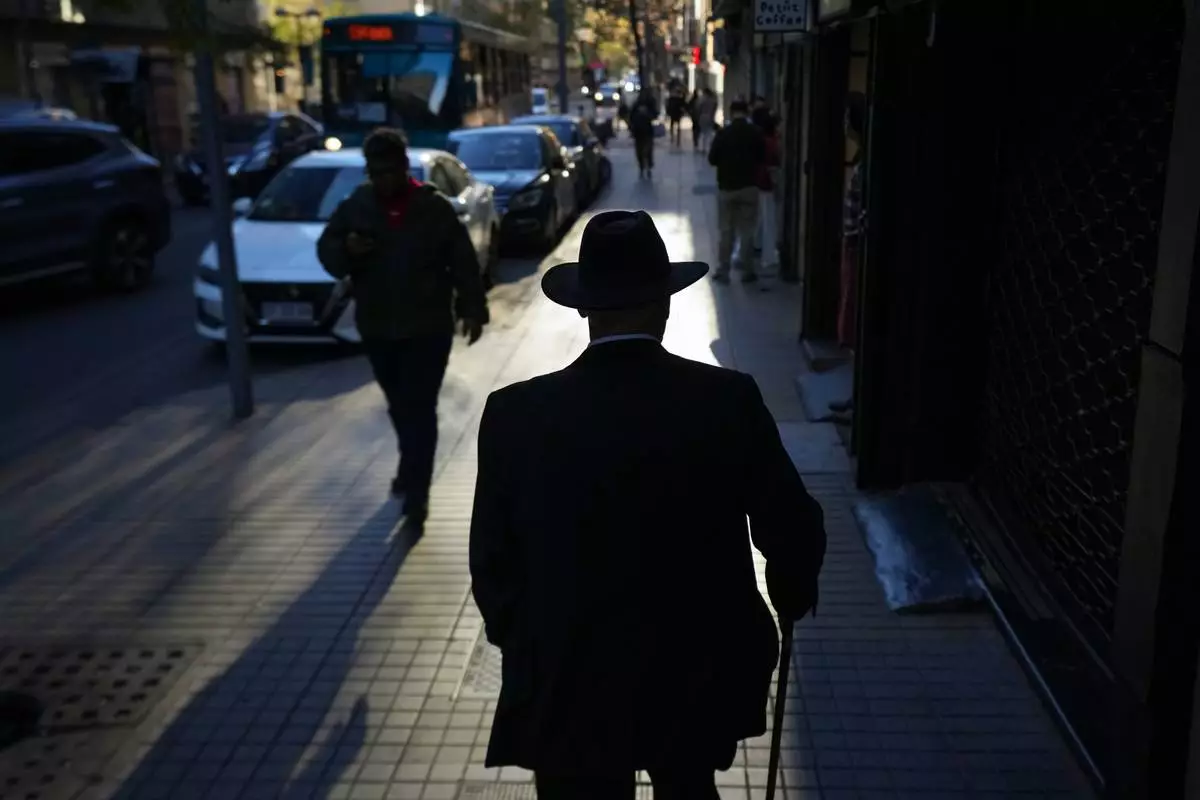 A man walks on a street in downtown Santiago, Chile, Wednesday, Oct. 1, 2025. (AP Photo/Esteban Felix)