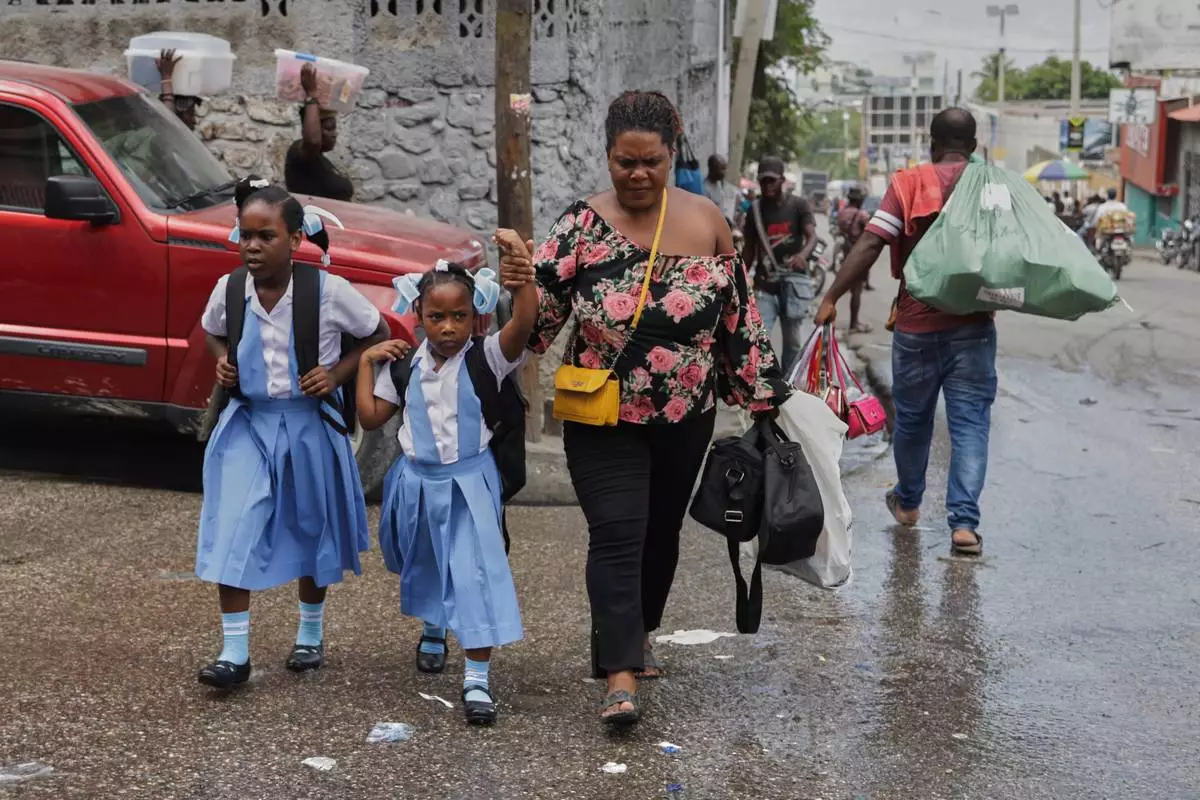 Children cross a street after school in Port-au-Prince, Haiti, Wednesday, Oct. 1, 2025. (AP Photo/Patrice Noel)