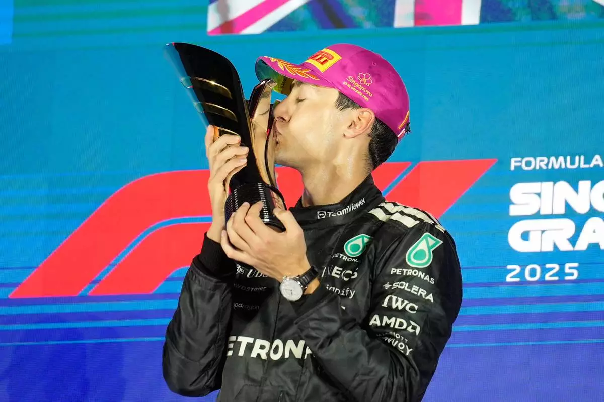 Mercedes driver George Russell of Britain kisses his trophy as he celebrates after winning the Singapore Formula One Grand Prix at the Marina Bay Street Circuit in Singapore, Sunday, Oct. 5, 2025. (AP Photo/Vincent Thian)