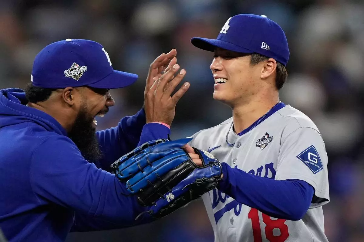 Los Angeles Dodgers pitcher Yoshinobu Yamamoto celebrates with right fielder Teoscar Hernández after throwing compete game against the Toronto Blue Jays in Game 2 of baseball's World Series, Saturday, Oct. 25, 2025, in Toronto. (AP Photo/Brynn Anderson)