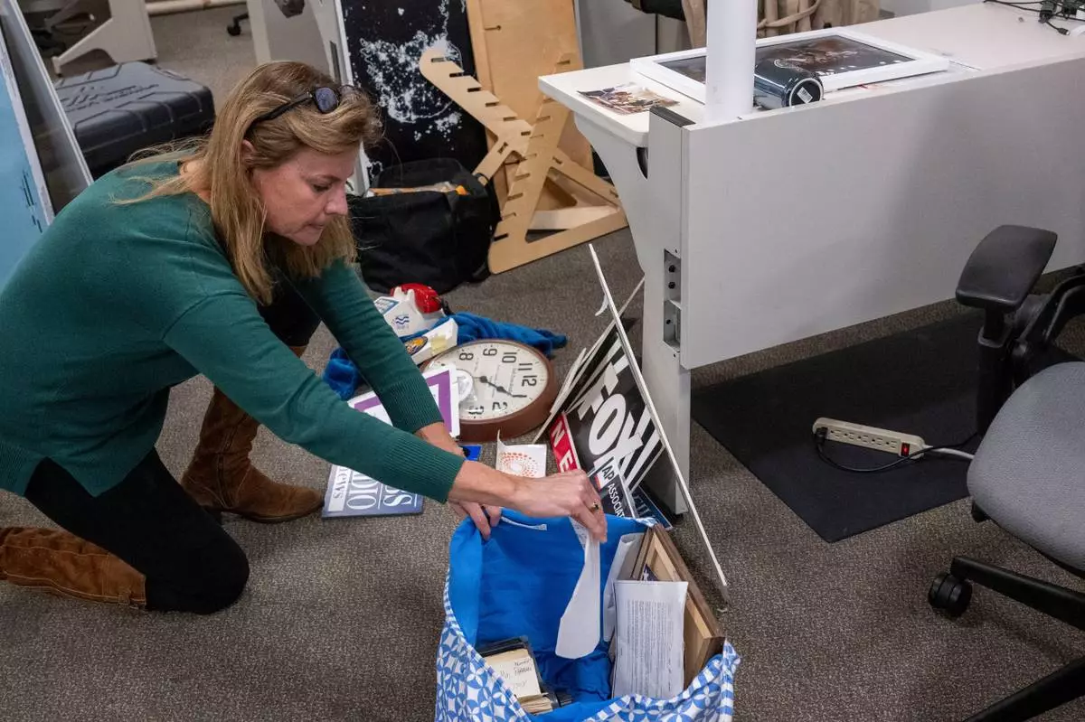 Washington Post reporter Tara Copp saves the name plaques from various news organizations as she and members of the media pack up their belongings in the press area in the Pentagon, Wednesday, Oct. 15, 2025 in Washington. (AP Photo/Kevin Wolf)