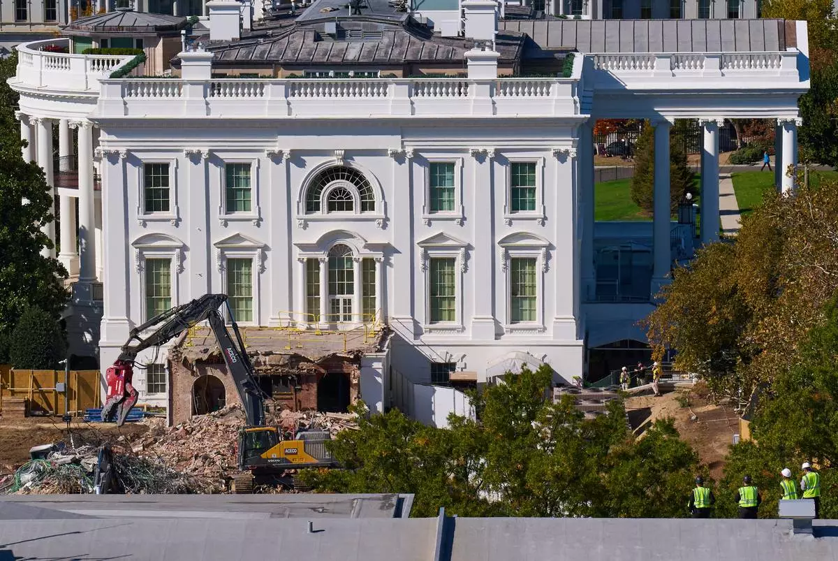 Construction workers, bottom right, atop the U.S. Treasury, watch watch as demolition continues on the East Wing of the White House to make room for a new ballroom, in Washington, Oct. 22, 2025. (AP Photo/Jacquelyn Martin)