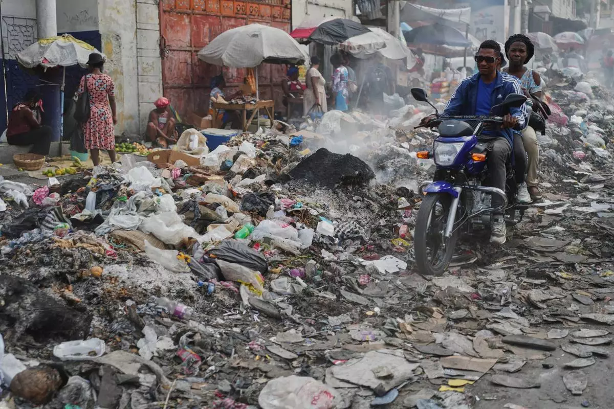 A motorcycle driver navigates a street covered with trash in downtown in Port-au-Prince, Haiti, Oct. 15, 2025. (AP Photo/Odelyn Joseph)