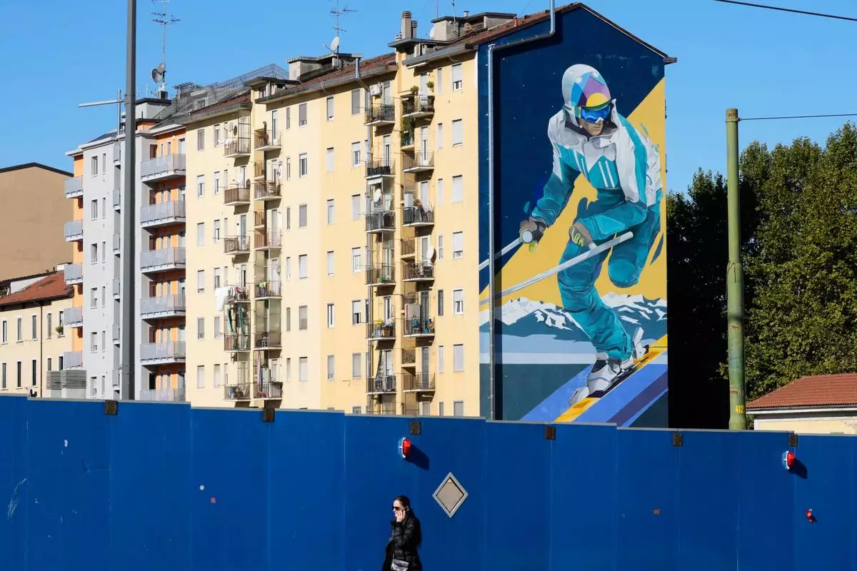 A giant mural depicting a skier is displayed on a wall of a building next to the Olympic village, in Milan, Italy, Friday, Oct. 24, 2025. (AP Photo/Luca Bruno)