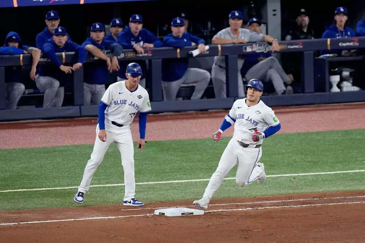 Toronto Blue Jays' Daulton Varsho runs past the Los Angeles Dodgers dugout after hitting his two run home run during the fourth inning in Game 1 of baseball's World Series, Friday, Oct. 24, 2025, in Toronto. (AP Photo/David J. Phillip)