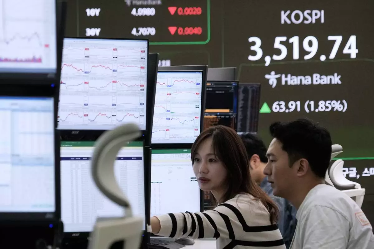 Currency traders watch monitors near a screen showing the Korea Composite Stock Price Index (KOSPI) at the foreign exchange dealing room of the Hana Bank headquarters in Seoul, South Korea, Thursday, Oct. 2, 2025. (AP Photo/Ahn Young-joon)