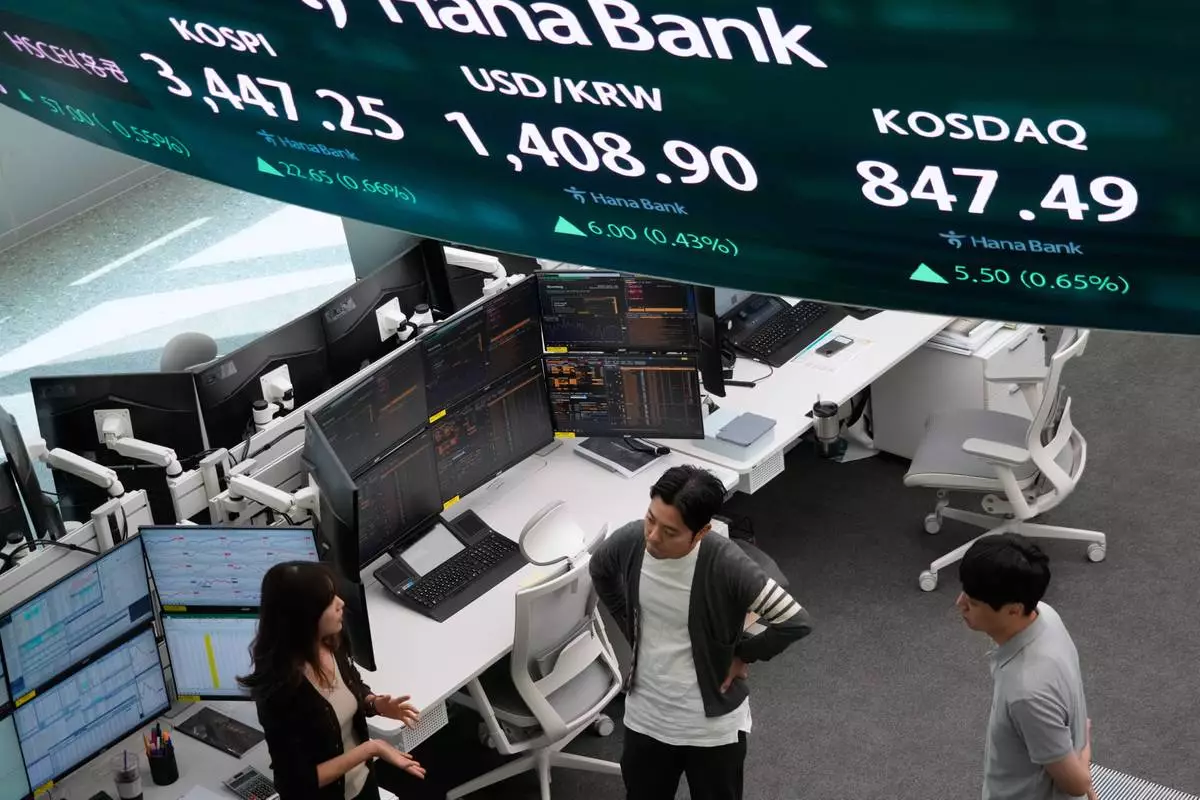 Currency traders work near a screen showing the Korea Composite Stock Price Index (KOSPI), top center, and the foreign exchange rate between U.S. dollar and South Korean won, top left, at the foreign exchange dealing room of the Hana Bank headquarters in Seoul, South Korea, Wednesday, Oct. 1, 2025. (AP Photo/Ahn Young-joon)