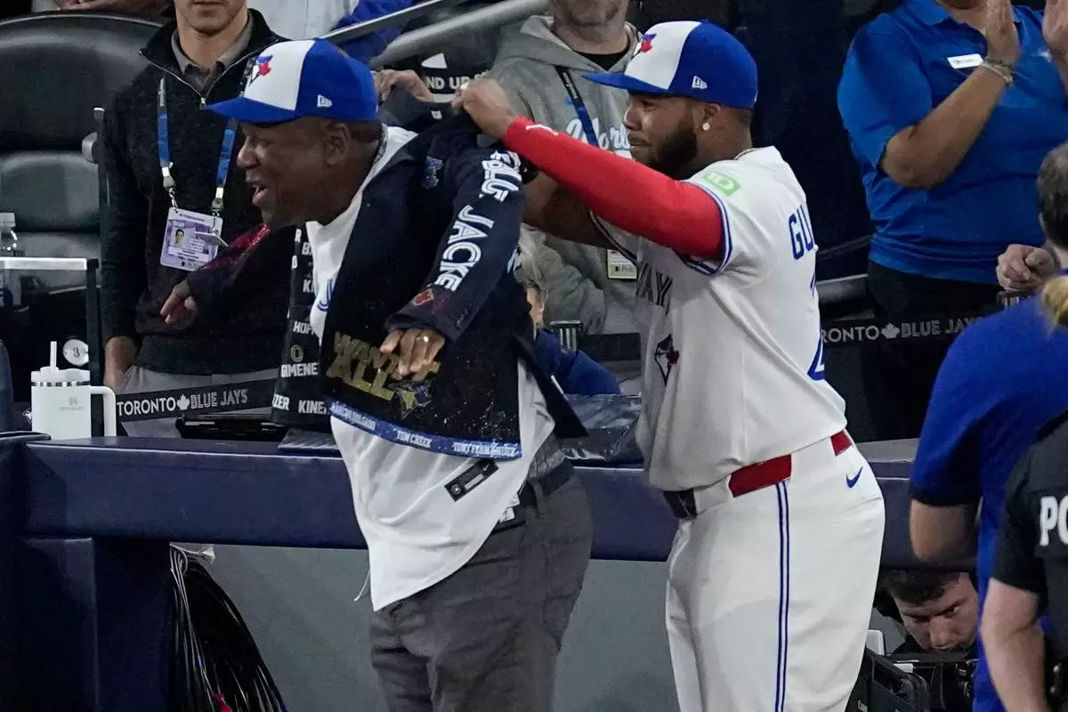Toronto Blue Jays' Vladimir Guerrero Jr.. puts the post season celebration jacket on former Blue Jay Joe Carter prior to Game 2 of baseball's World Series against the Los Angeles Dodgers, Saturday, Oct. 25, 2025, in Toronto. (AP Photo/David J. Phillip)