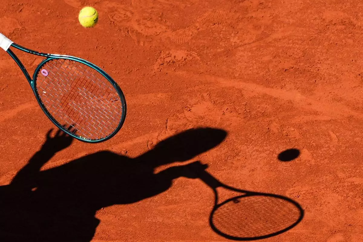 FILE - A player casts a shadow upon the court as they play a shot during the French Tennis Open, Friday, May 30, 2025, at the Roland-Garros stadium in Paris. (AP Photo/Lindsey Wasson, File)