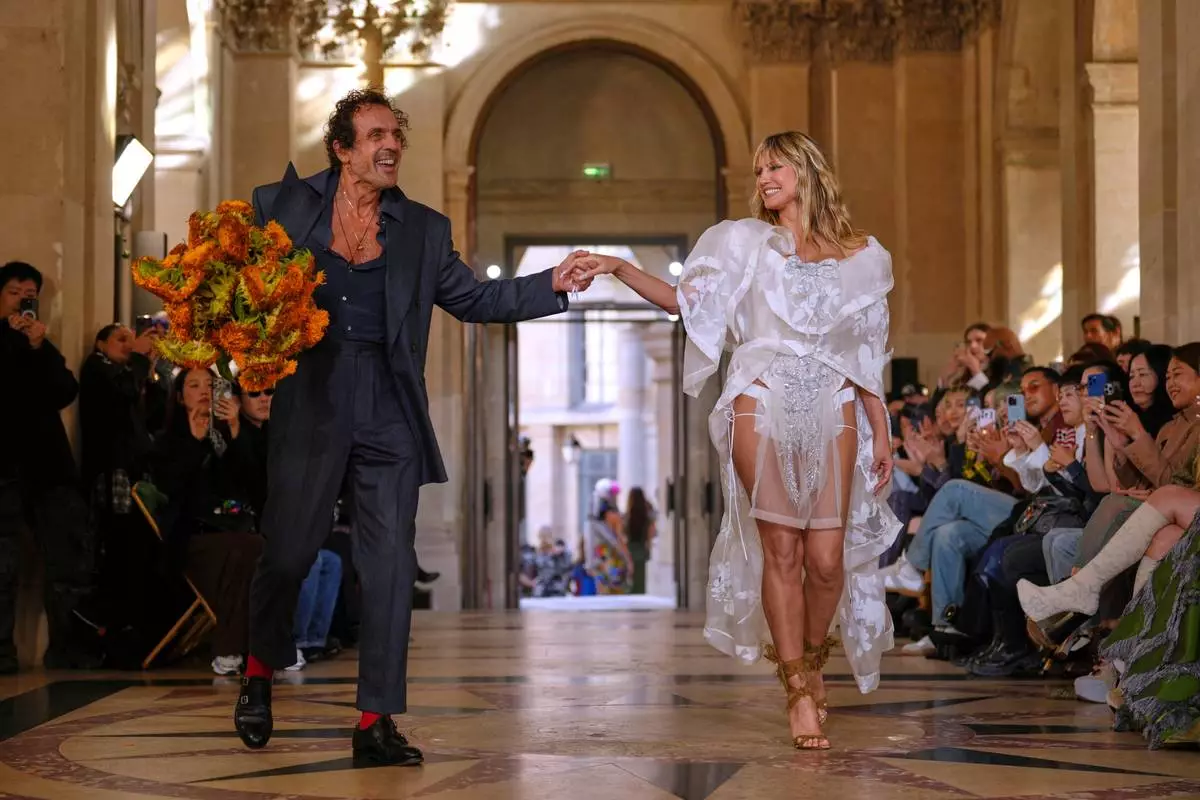 Designer Andreas Kronthaler, left, accepts applause as he holds the hand of Heidi Klum as part of the Vivienne Westwood Spring/Summer 2026 collection presented in Paris, Saturday, Oct. 4, 2025. (AP Photo/Aurelien Morissard)