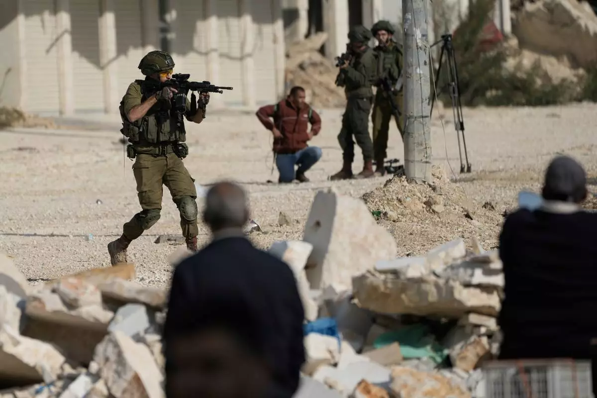 FILE - An Israeli soldier aims his weapon to disperse people taking part in a protest calling for the return of displaced Palestinians to their houses in the Nur Shams refugee camp in the West Bank city of Tulkarem, Nov. 18, 2025. (AP Photo/Majdi Mohammed, File)