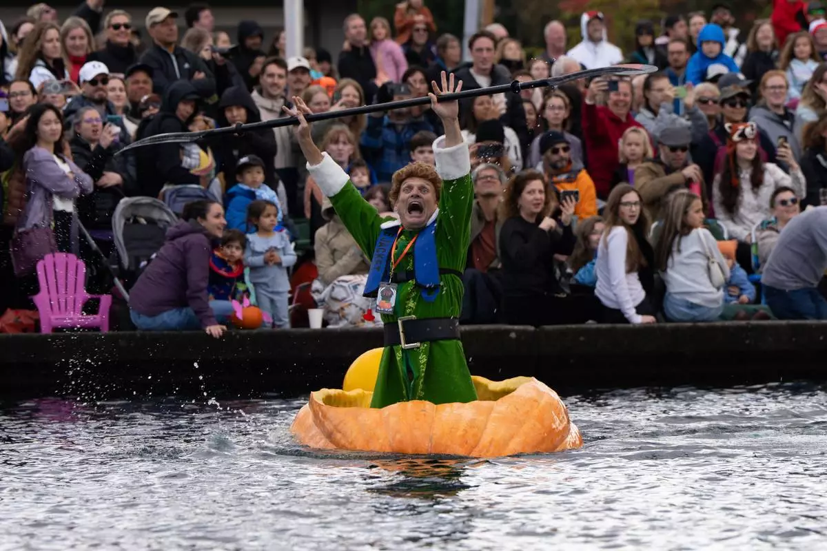 FILE - Gary Kristensen, dressed up as the character Buddy from the holiday movie "Elf," celebrates after winning a race during the West Coast Giant Pumpkin Regatta in Tualatin, Ore., Oct. 19, 2025. (AP Photo/Jenny Kane, File)
