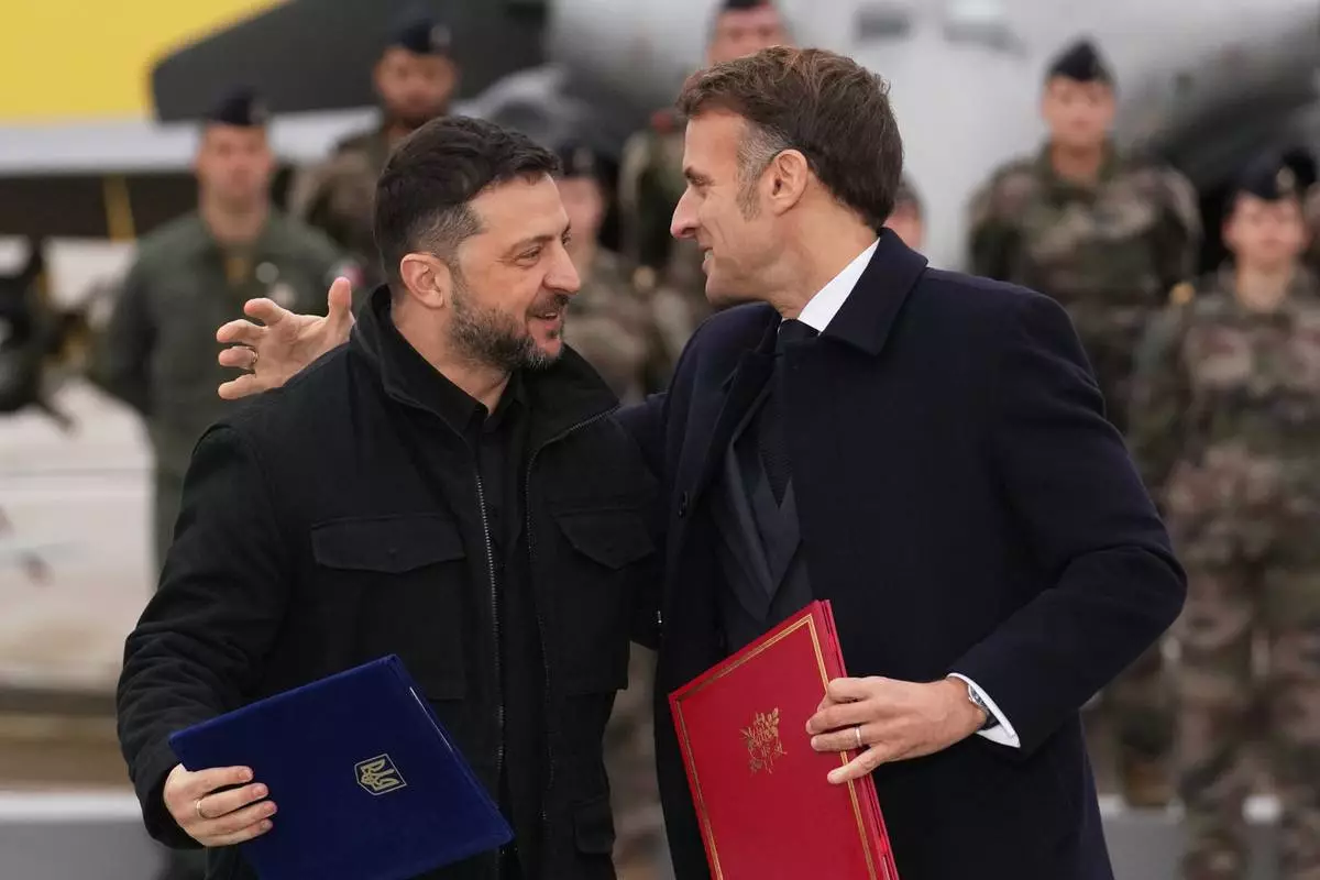 French President Emmanuel Macron, right, and Ukrainian President Volodymyr Zelenskyy hug after signing an agreement Monday, Nov. 17, 2025 at the Villacoublay air base near Paris. (AP Photo/Christophe Ena, Pool)