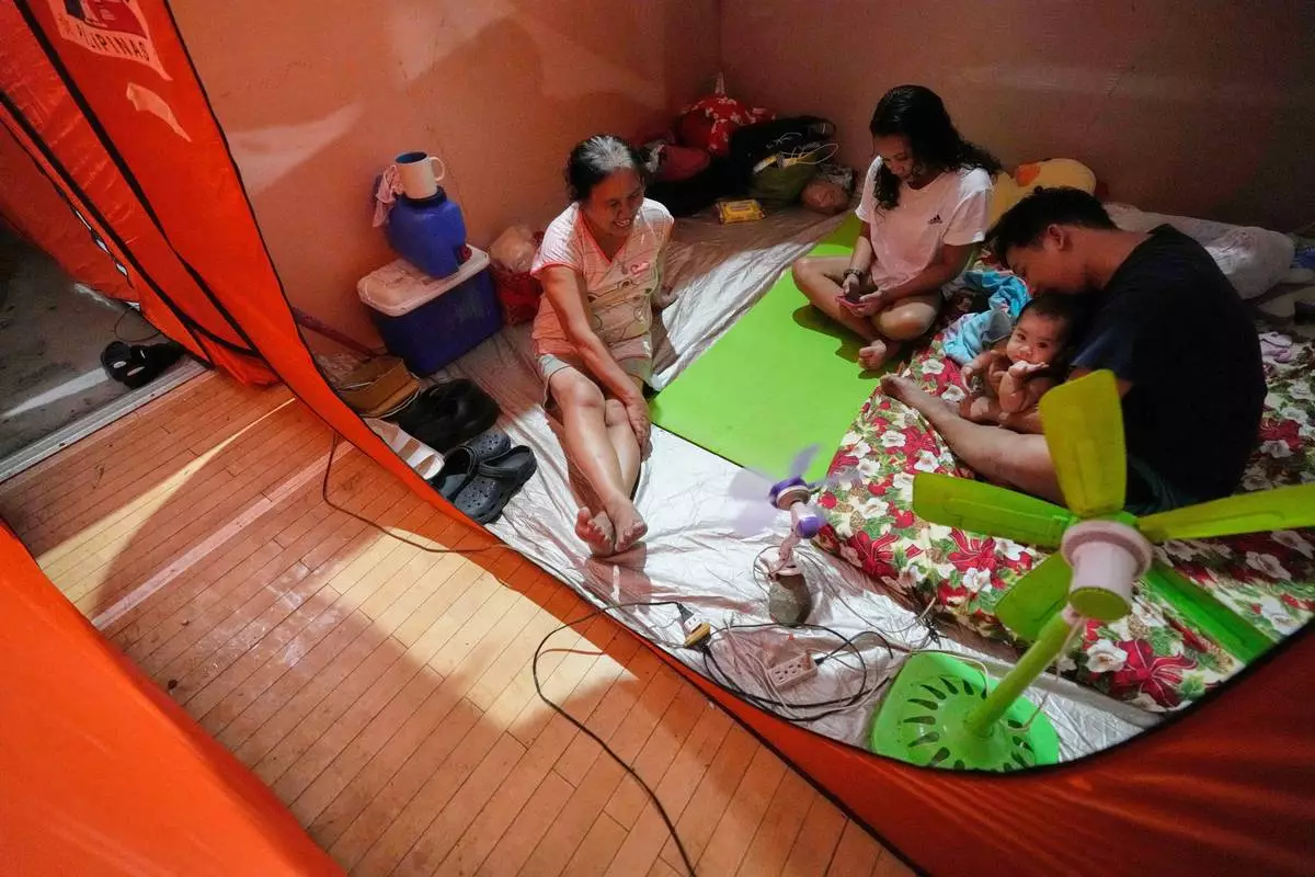 Judie Delector, right, and his family stay inside a tent at an evacuation center as Typhoon Fung-wong enters the country on Sunday, Nov. 9, 2025 in Quezon city, Philippines. (AP Photo/Aaron Favila)