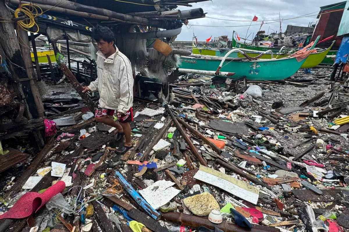 A man walks on debris washed ashore due to Typhoon Fung-wong along a coastal village on Monday, Nov. 10, 2025, in Navotas, Philippines. (AP Photo/Aaron Favila)