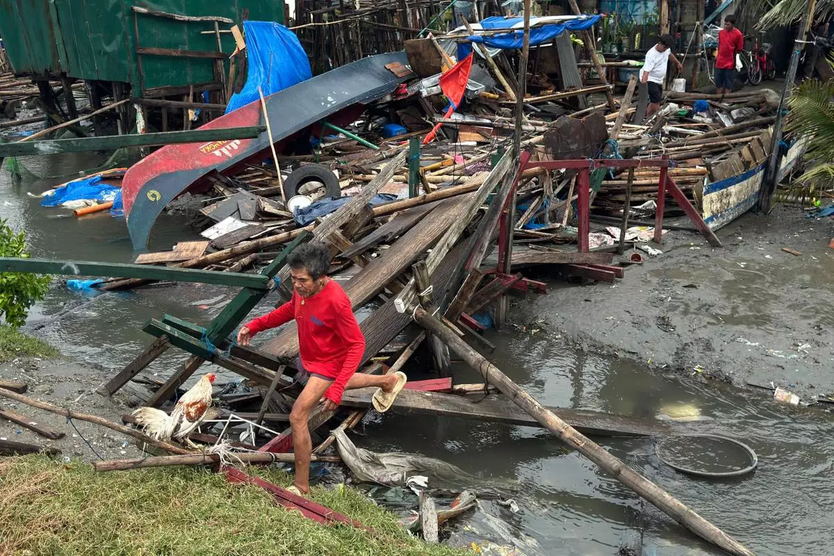 A man crosses a damaged bridge and house due to Typhoon Fung-wong along a coastal village on Monday, Nov. 10, 2025, in Navotas, Philippines. (AP Photo/Aaron Favila)