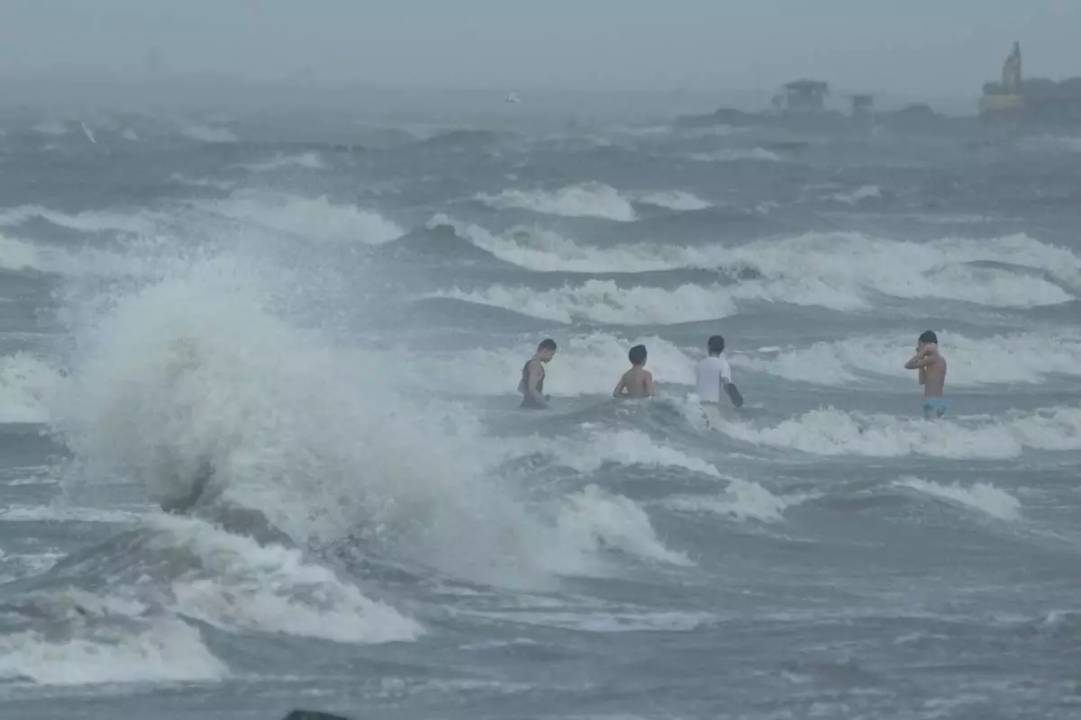 Men swim despite strong waves due to Typhoon Fung-wong along a coastal village on Monday, Nov. 10, 2025, in Navotas, Philippines. (AP Photo/Aaron Favila)