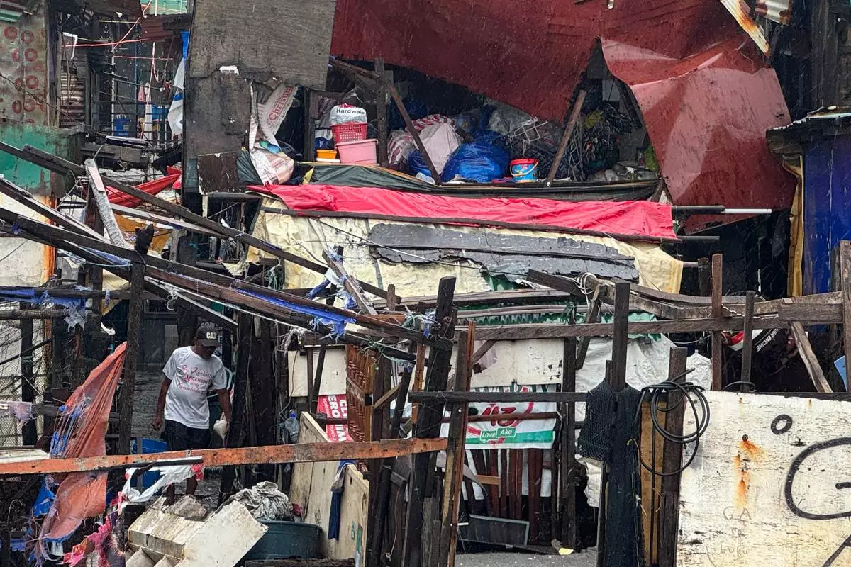 A man checks a damaged house due to Typhoon Fung-wong along a coastal village on Monday, Nov. 10, 2025, in Navotas, Philippines. (AP Photo/Aaron Favila)