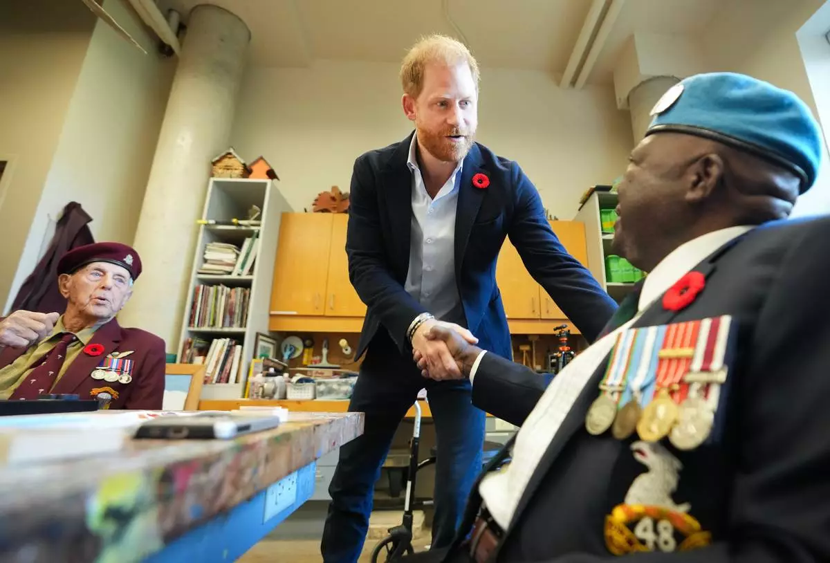 CORRECTS NAME FROM OSSIE TO OZZIE - Prince Harry, center, shakes hands with war veteran Ozzie Reece as he meets with some of Canada's oldest veterans, joining them in a creative arts program at Sunnybrook Hospital's veterans center in Toronto, Thursday, Nov. 6, 2025. (Nathan Denette /The Canadian Press via AP)