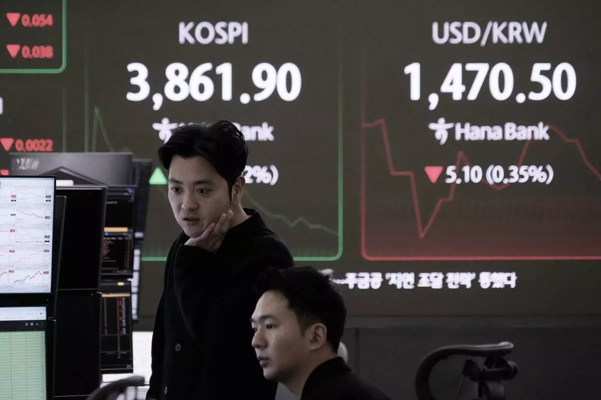 Currency traders watch monitors near a screen showing the Korea Composite Stock Price Index (KOSPI) and the foreign exchange rate between U.S. dollar and South Korean won, right, at the foreign exchange dealing room of the Hana Bank headquarters in Seoul, South Korea, Monday, Nov. 24, 2025. (AP Photo/Ahn Young-joon)