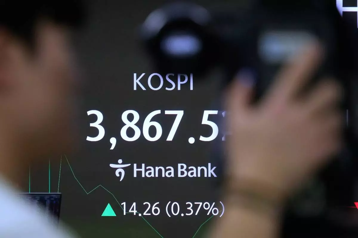 A TV camera man stands near a screen showing the Korea Composite Stock Price Index (KOSPI) at the foreign exchange dealing room of the Hana Bank headquarters in Seoul, South Korea, Monday, Nov. 24, 2025. (AP Photo/Ahn Young-joon)