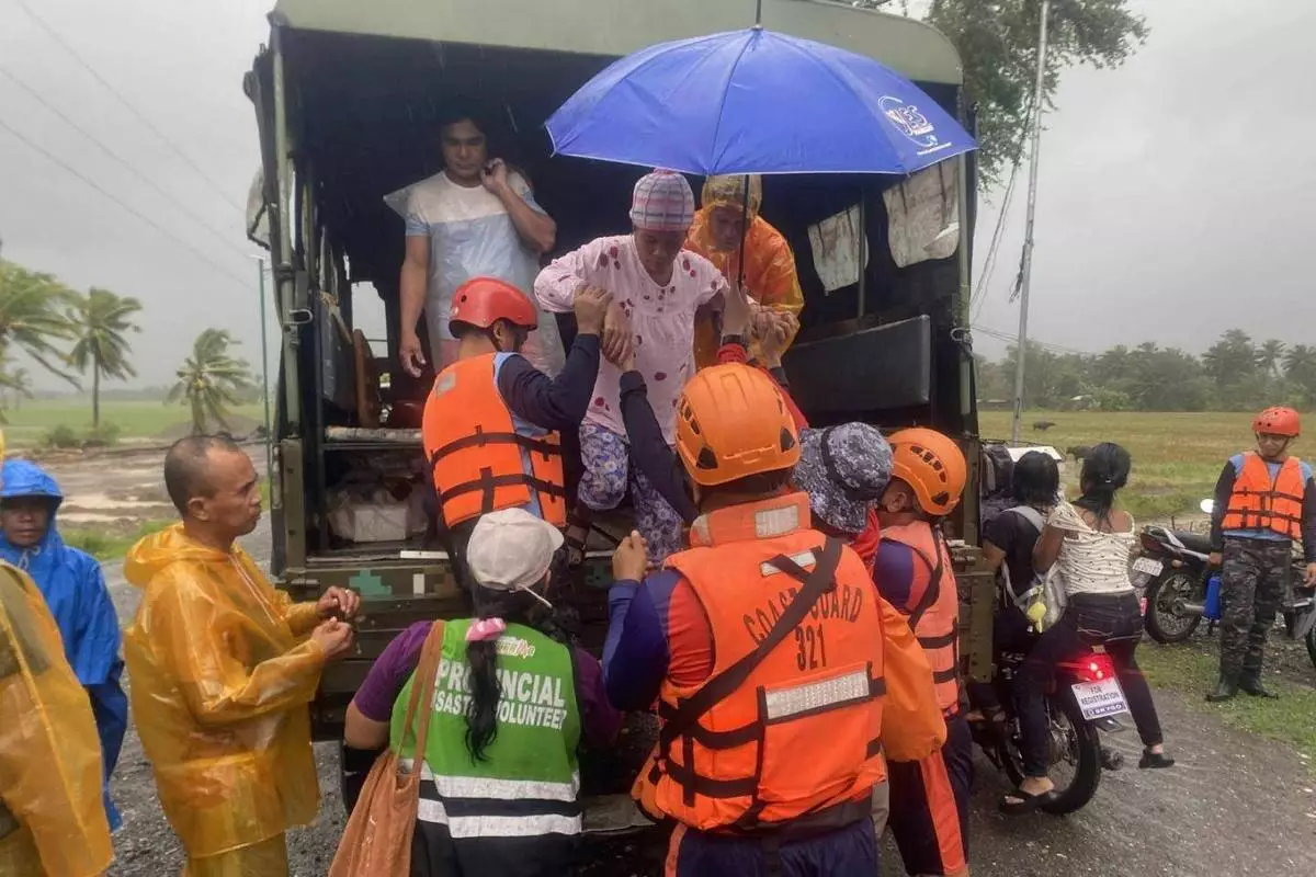 In this photo provided by the Philippine Coast Guard, rescuers evacuate residents in Sablayan, Occidental Mindoro province of the Philippines as Typhoon Fung-wong batters the country on Sunday, Nov. 9 2025. (Philippine Coast Guard via AP)