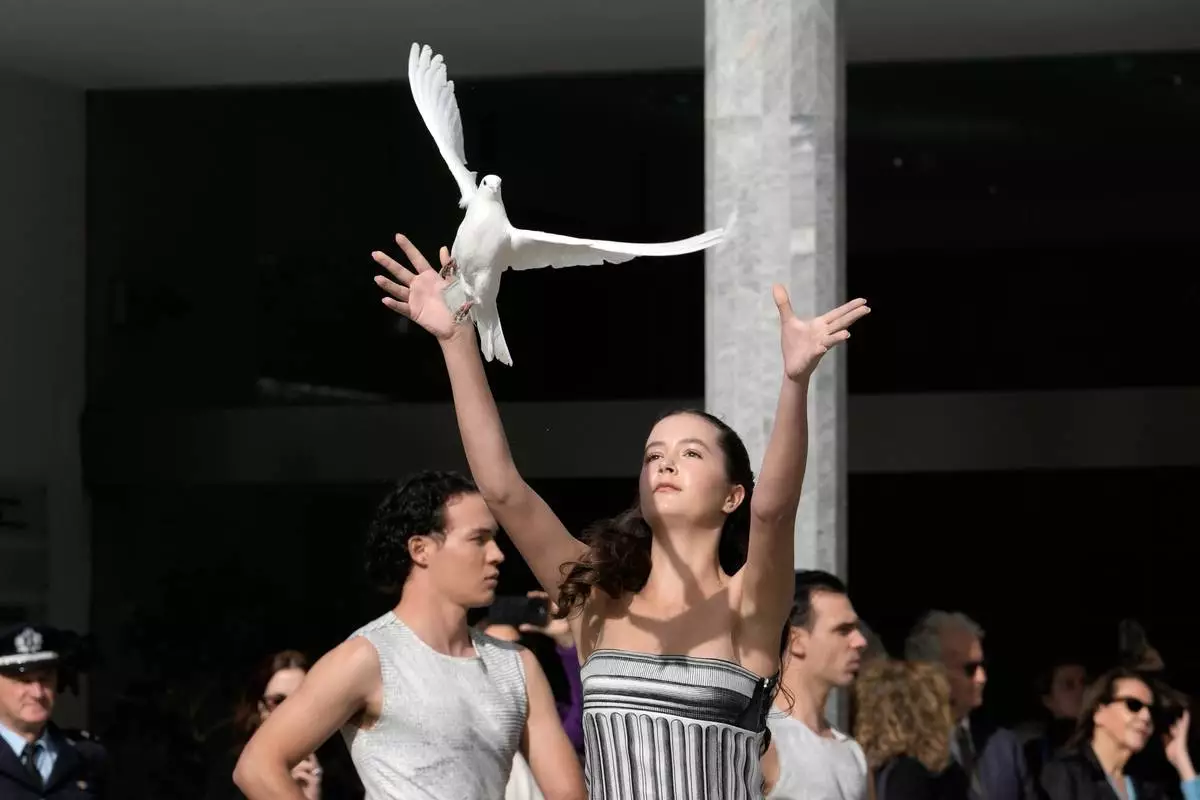A girl releases a white pigeon during the start of the torch relay after the ceremony of the flame lighting for the Milan Cortina 2026 Winter Olympics, at the archaeological museum of Olympia, Greece, Wednesday, Nov. 26, 2025. (AP Photo/Petros Giannakouris)