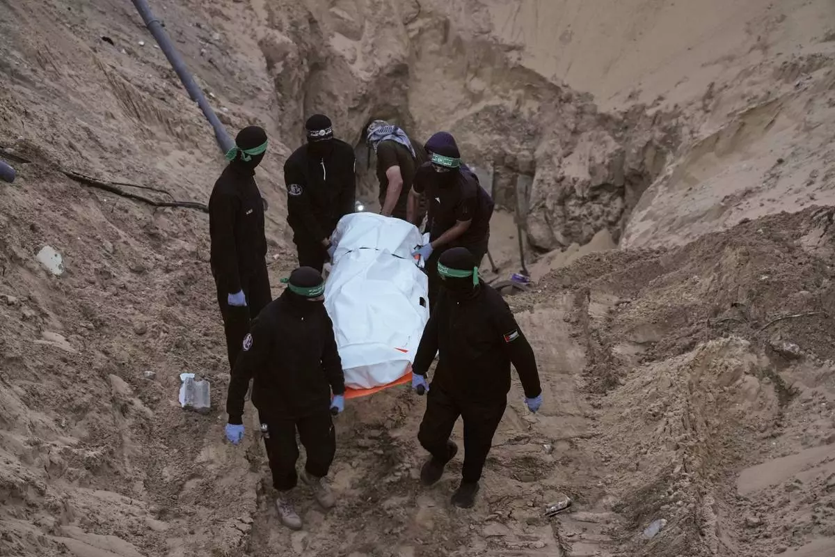FILE - Hamas militants carry a white bag believed to contain a body, after retrieving it from a tunnel during a search for the remains of hostages in Hamad City, Khan Younis, in southern Gaza, Tuesday, Oct. 28, 2025. (AP Photo/Jehad Alshrafi, File)