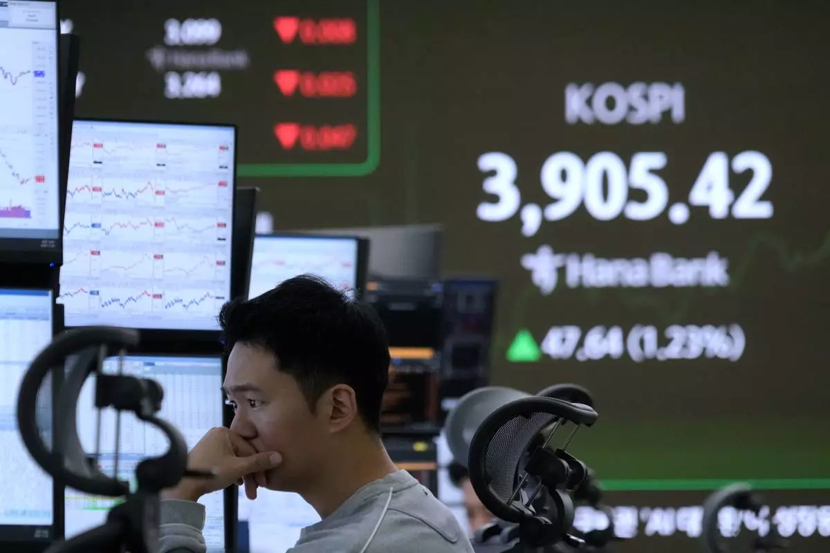A currency trader watches monitors near a screen showing the Korea Composite Stock Price Index (KOSPI) at the foreign exchange dealing room of the Hana Bank headquarters in Seoul, South Korea, Wednesday, Nov. 26, 2025. (AP Photo/Ahn Young-joon)