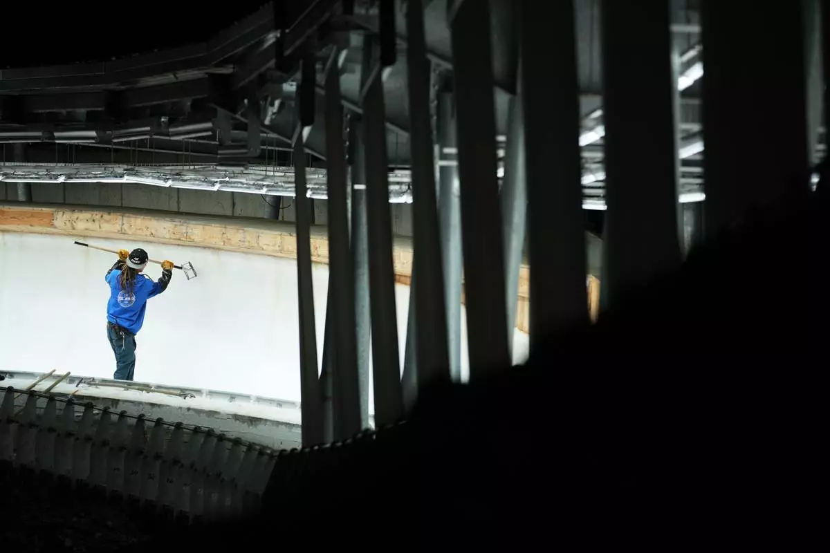 A man works on the track ahead of a three-day skeleton and bobsled World Cup stage and Olympic test event in Cortina D'Ampezzo, Italy, Wednesday, Nov. 19, 2025. (AP Photo/Andrew Medichini)