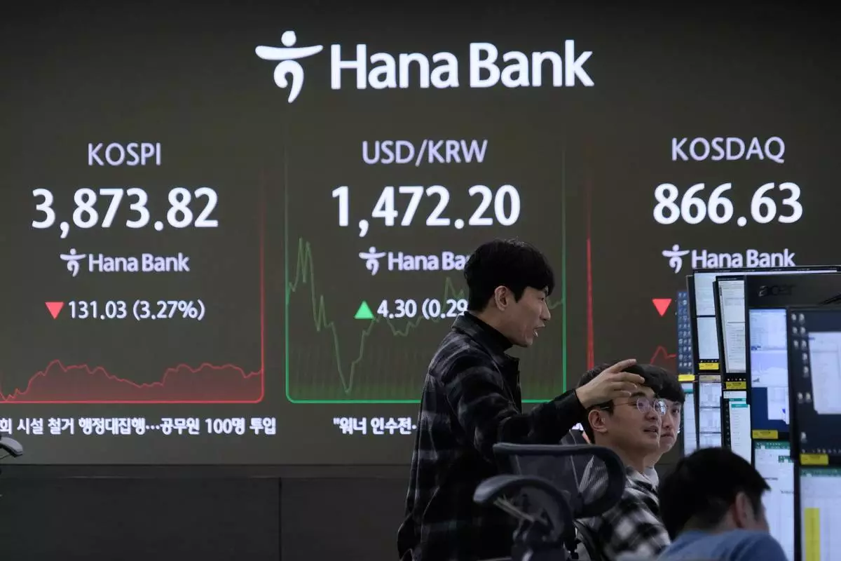 Currency traders work near a screen showing the Korea Composite Stock Price Index (KOSPI), left, and the foreign exchange rate between U.S. dollar and South Korean won, center, at the foreign exchange dealing room of the Hana Bank headquarters in Seoul, South Korea, Friday, Nov. 21, 2025. (AP Photo/Ahn Young-joon)