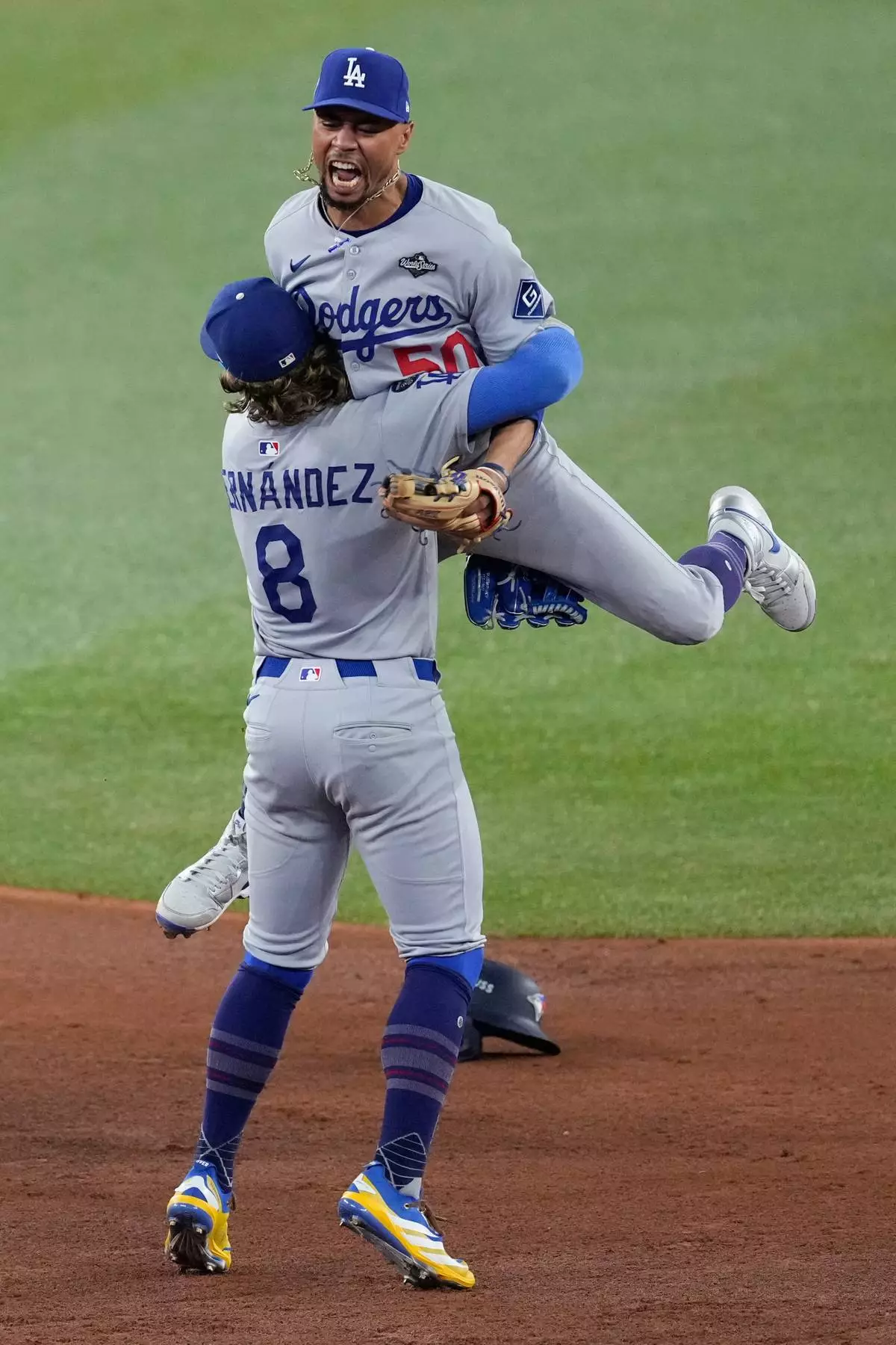Los Angeles Dodgers' Mookie Betts leaps into the arms of Kiké Hernández (8) after Toronto Blue Jays' Addison Barger, right, was forced out to end Game 6 of baseball's World Series, Friday, Oct. 31, 2025, in Toronto. (AP Photo/Ashley Landis)
