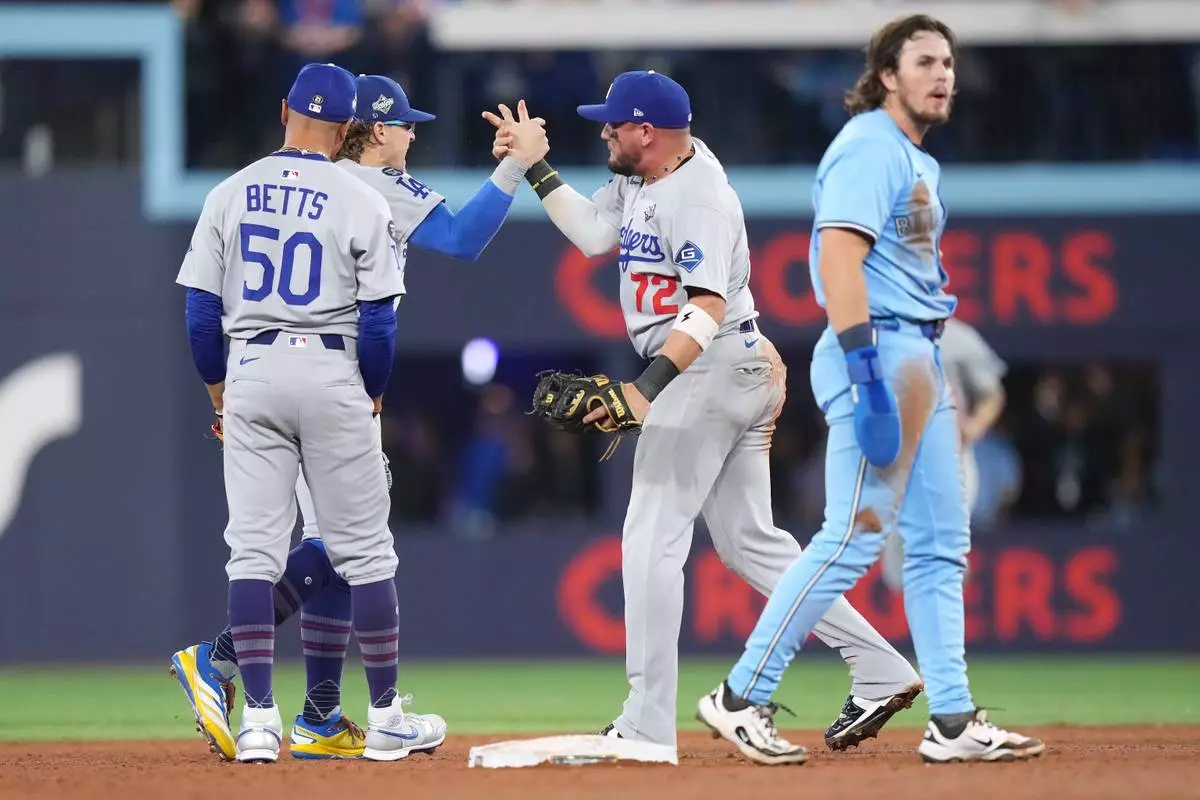 Los Angeles Dodgers second baseman Miguel Rojas (72) celebrates with shortstop Mookie Betts (50) and left fielder Enrique Hernández (8) after forcing out Toronto Blue Jays' Addison Barger (47) to end the game during ninth inning Game 6 World Series playoff MLB baseball action in Toronto on Friday, Oct. 31, 2025. (Nathan Denette/The Canadian Press via AP)