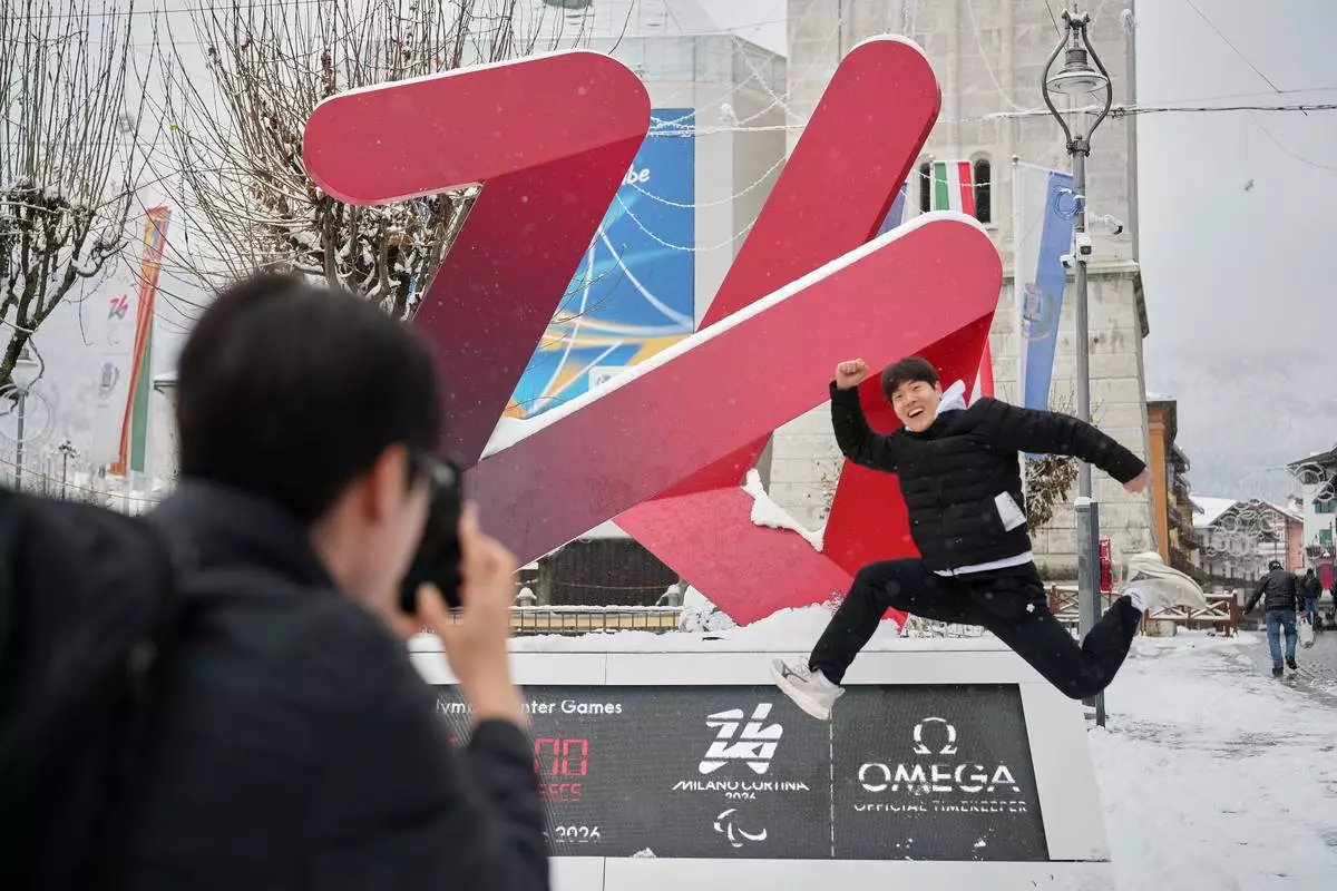 South Korean skeleton athlete Jung Seunggi, right, has a photo taken in front of the Milan Cortina Winter Olympics countdown clock, in Cortina D'Ampezzo, Thursday, Nov. 20, 2025. (AP Photo/Andrew Medichini)