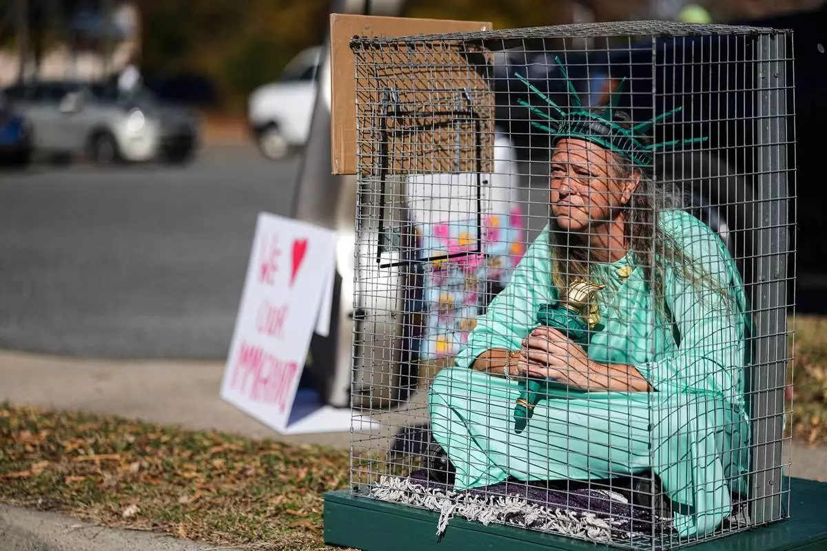 Shana Blake sits in a cage dressed as the Statue of Liberty to protest federal law enforcement presence in Charlotte, N.C. Monday, Nov. 17, 2025. (AP Photo/Matt Kelley)