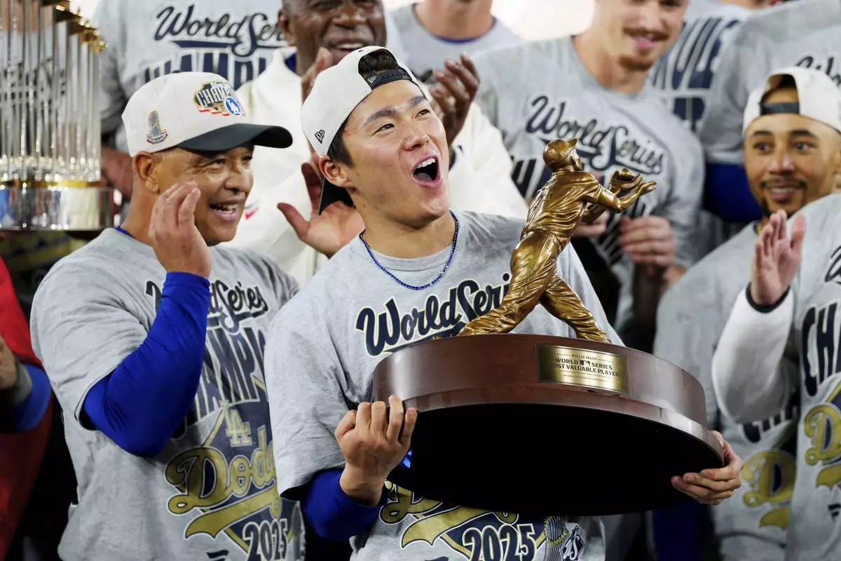 Los Angeles Dodgers pitcher Yoshinobu Yamamoto lifts the World Series MVP trophy as the Dodgers celebrate after defeating the Toronto Blue Jays in Game 7 of baseball's World Series, Sunday, Nov. 2, 2025, in Toronto. (Frank Gunn/The Canadian Press via AP)